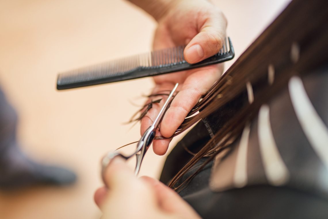 Close-up of a  man hairdresser cutting the hair of a woman.